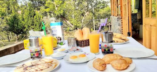 a table topped with plates of food and orange juice at Sa House Bac Ha in Bắc Hà