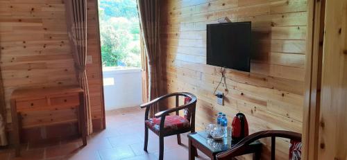 uma sala de estar com uma televisão numa parede de madeira em Sa House Bac Ha em Bac Hà