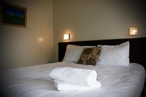 a bed with white sheets and pillows in a room at Birchwood Spa Motel in Rotorua