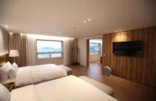 a hotel room with two beds and a flat screen tv at Am Ort Hotel in Yeosu