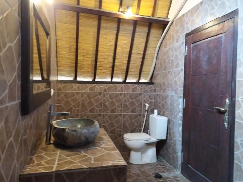 a bathroom with a sink and a toilet and a window at Kusuka Bungalow in Gili Trawangan