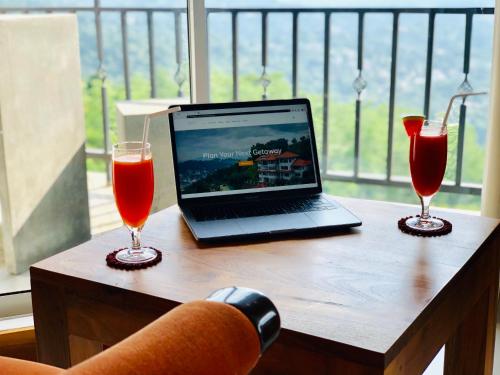 a laptop computer sitting on a table with two glasses at The Heaven's Villa Kandy in Kandy