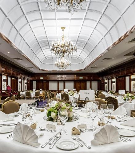 a dining room with white tables and a chandelier at Taj 51 Buckingham Gate Suites and Residences in London
