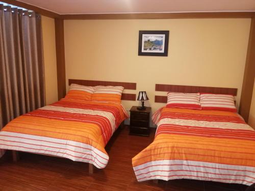 - 2 lits installés l'un à côté de l'autre dans une chambre dans l'établissement Nasca Travel One Hostel, à Nazca