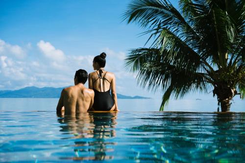 Ein Mann und eine Frau sitzen im Wasser im Pool in der Unterkunft Anantara Bophut Koh Samui Resort in Bophut 