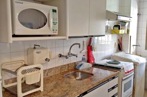 una pequeña cocina con fregadero y microondas en Apto Ocean Drive - Praia da Barra, en Río de Janeiro