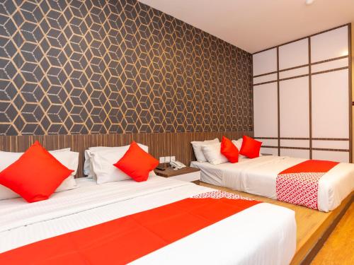 two beds in a room with red and white pillows at De Sweet Boutique Hotel in Johor Bahru
