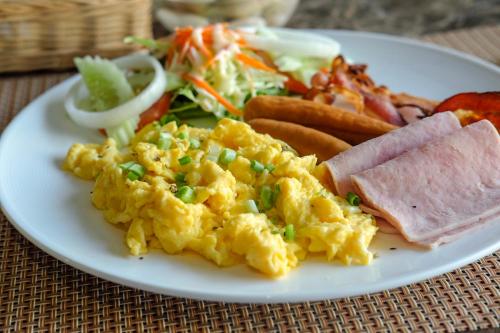 a plate of breakfast food with eggs ham and salad at Methavalai Residence Hotel in Bangkok