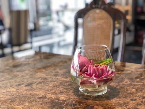 a glass vase with a flower in it on a table at Methavalai Residence Hotel in Bangkok