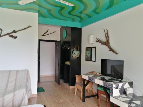 Habitación con cama, mesa y TV. en Hotel de la Plage, en Kep