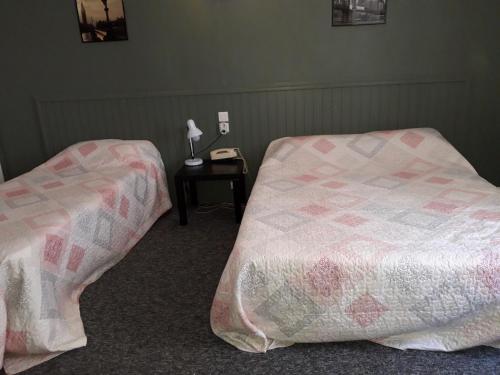 two beds in a room with a phone and a table at Hôtel des Jacobines in Chalon-sur-Saône