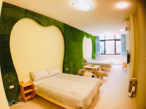 ein Schlafzimmer mit einer grünen Wand, einem Bett und einem Tisch in der Unterkunft Greenonly Homestay in Tainan