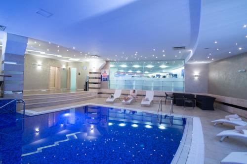 una habitación de hotel con una piscina con sillas y un bar en Rosslyn Dimyat Hotel Varna, en Varna