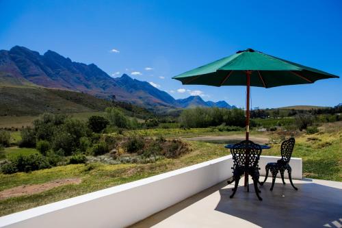 einen Tisch und zwei Stühle mit Sonnenschirm auf dem Balkon in der Unterkunft Joubertsdal Country Estate in Swellendam