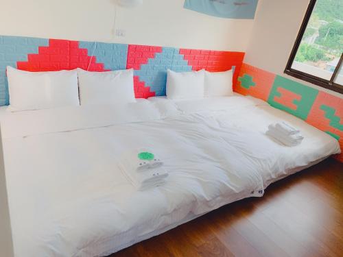 Cama blanca grande en habitación con cabecero colorido en 台東醇旅旅宿-民宿編號1417, en Lijia