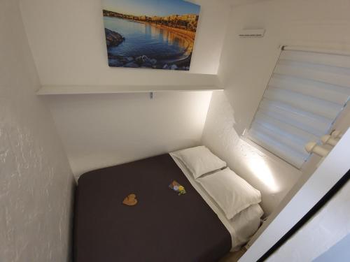 - un petit lit dans une petite chambre avec un tableau dans l'établissement T2 rez de jardin front de mer, à Cannes