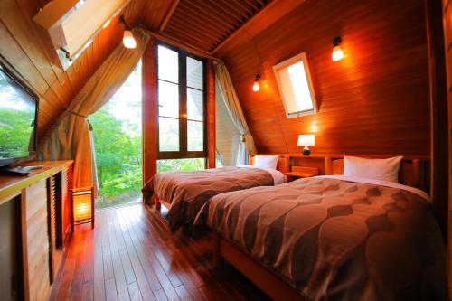 a bedroom with two beds in a room with windows at Sakura Sakura Onsen in Kirishima