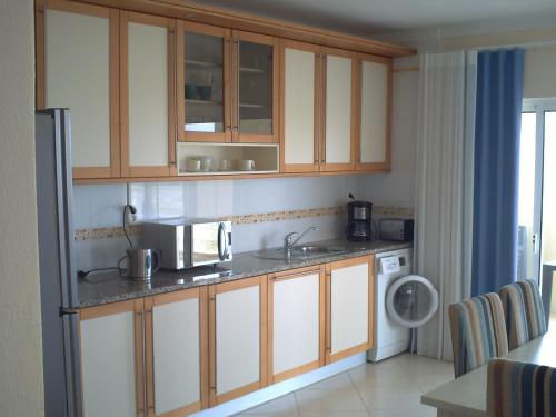 a kitchen with wooden cabinets and a microwave at Apartamento Vila Marachique in Alvor