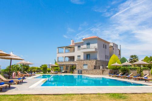 a villa with a swimming pool in front of a building at Marini Luxury Apartments and Suites in Aegina Town