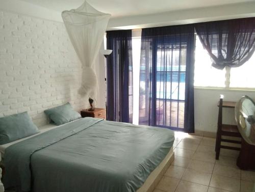 a bedroom with a large bed and a window at Hotel Restaurant Hellenique Appartements in Kigali