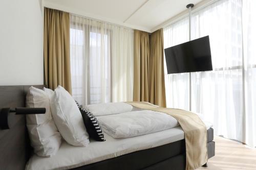 a bedroom with a bed with white pillows and a television at Corsendonk Turnova in Turnhout