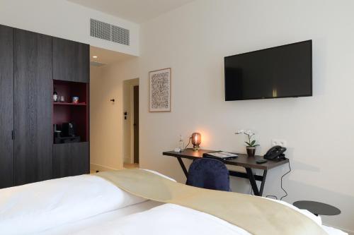 a bedroom with a bed and a desk with a television at Corsendonk Turnova in Turnhout