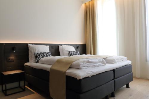 a bedroom with a large bed with white sheets and pillows at Corsendonk Turnova in Turnhout