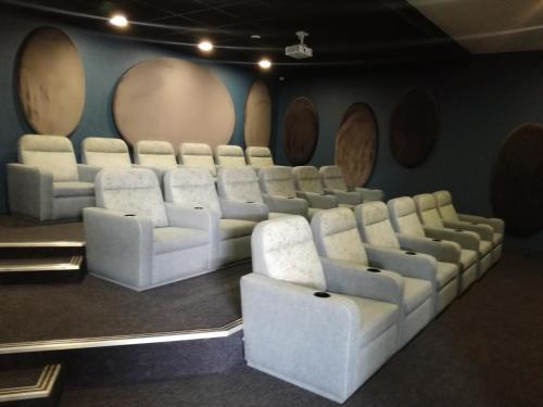 a cinema room with white chairs and a wall with barrels at The Blyde - Crystal Lagoon Penthouse Apartment in Pretoria