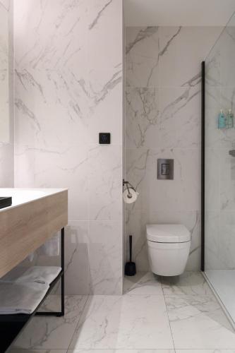 a white bathroom with a toilet and a shower at Corsendonk Turnova in Turnhout