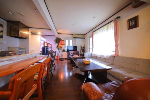 a restaurant with a couch and a table and chairs at Sakura Sakura Onsen in Kirishima