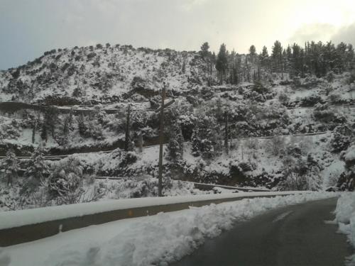 a road covered in snow next to a mountain at Wanderer's Lodge in Sparti