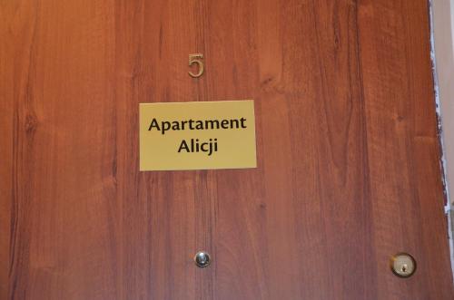 un panneau sur une porte en bois avec le mot appartement alpha dans l'établissement Apartament Alicji, à Ełk