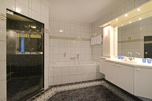 een badkamer met een bad, een wastafel en een douche bij Fletcher Hotel - Restaurant Elzenduin in Ter Heijde