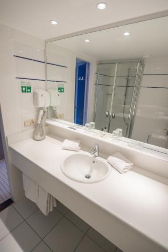 a bathroom with a sink and a large mirror at Ostend Hotel in Ostend