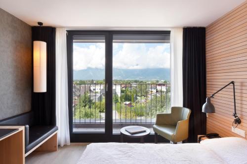 a bedroom with a bed and a chair and a window at Hotel Weisses Kreuz in Feldkirch