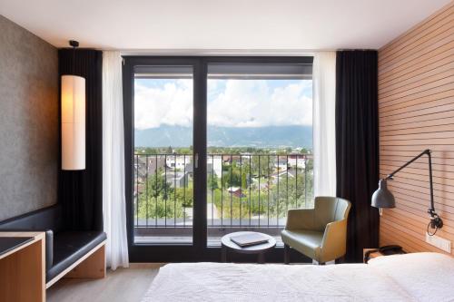 ein Schlafzimmer mit einem Bett, einem Stuhl und einem Fenster in der Unterkunft Hotel Weisses Kreuz in Feldkirch