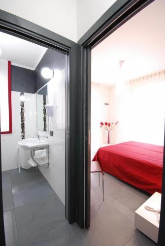a bedroom with a red bed and a bathroom with a sink at Olympus Resort in Alba Adriatica