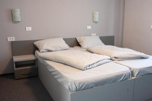 two beds in a room with white sheets and pillows at Pensiunea Vlad in Arad