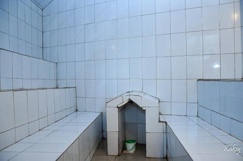 a white tiled room with a toilet in it at Dreamz Recreation Center in Jinja