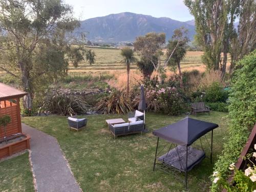 a garden with chairs and a table and mountains in the background at Brook House B&B & Cottages in Kaikoura
