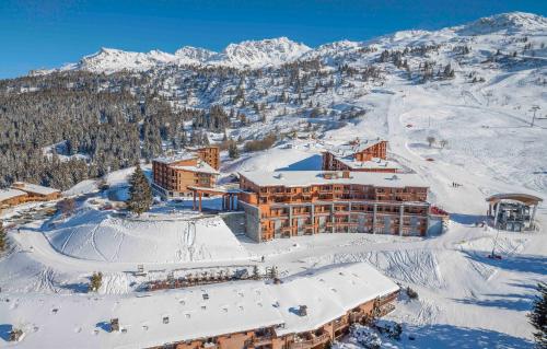 a hotel in the snow with a mountain in the background at Résidence Odalys Edenarc in Arc 1800
