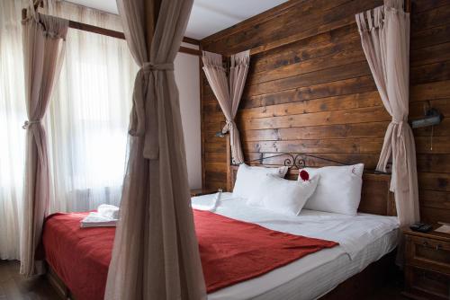 a bedroom with a bed with a wooden wall at Zlaten Rozhen Family Hotel in Rozhen