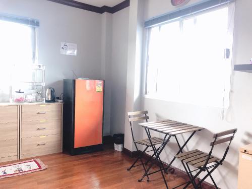 a kitchen with a refrigerator and a table and chairs at 24 Hostel Donmuang in Thung Si Kan