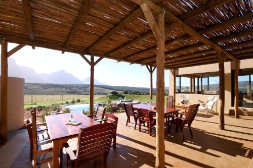 eine Außenterrasse mit Tischen und Stühlen und Bergblick in der Unterkunft Oudebosch Guest Farm in Riversdale