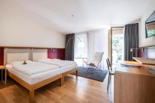 a bedroom with a bed and a desk and a chair at Ringhotel Schorfheide, Tagungszentrum der Wirtschaft in Joachimsthal
