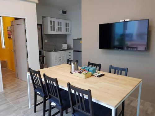 a dining room table with chairs and a television on a wall at The Cube Resort in Chanthaburi