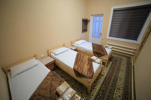 2 camas en una habitación pequeña con ventana en PARVIZ GUEST HOUSE, en Bukhara