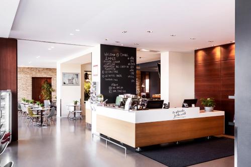 a restaurant with a counter and tables and chairs at Hotel Daniel Graz - Smart Luxury Near City Centre in Graz