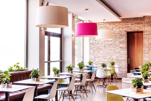 un restaurante con mesas, sillas y macetas en Hotel Daniel Graz - Smart Luxury Near City Centre en Graz
