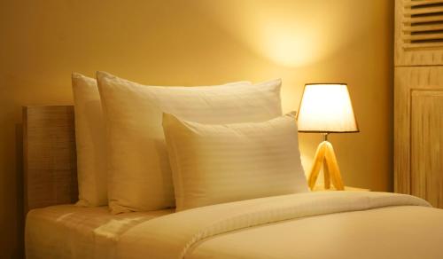 a bed with white pillows next to a lamp at Olinia Airport Hotel in Katunayake